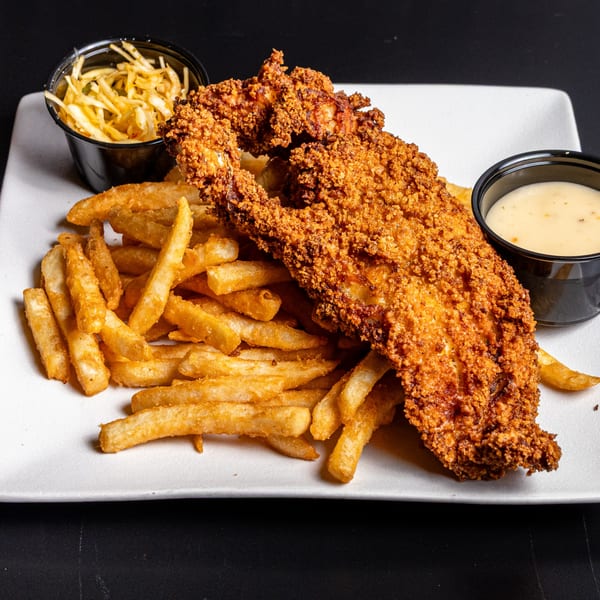 Crispy fried chicken tenders with a side of golden french fries, coleslaw, and dipping sauce.
