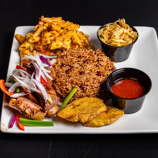 A white plate with ribs, rice and beans, macaroni, plantains, and two small cups of sauce.